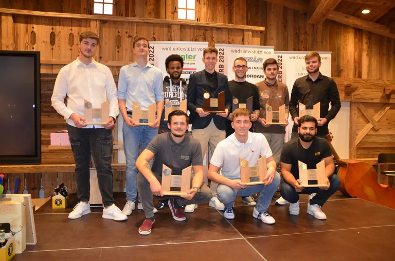Die Teilnehmer des Bundesleistungswettbewerbs in Ehingen 2022. Die Gewinner halten den Pokal aus dunklem Holz in Händen: Franz Dybek (links) und Noel-Eric Gierich (rechts).