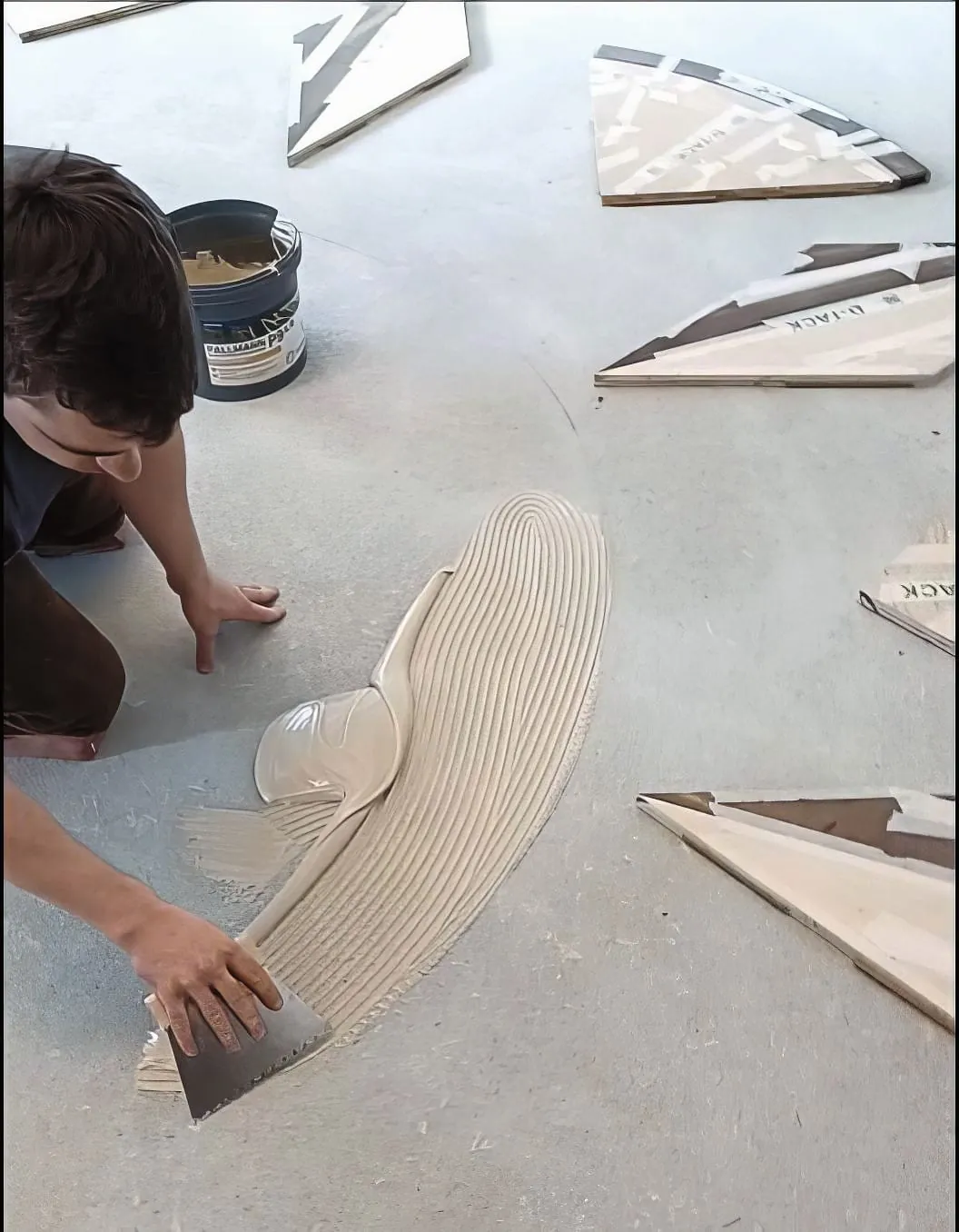 Verleger streicht Klebstoff auf Estrich