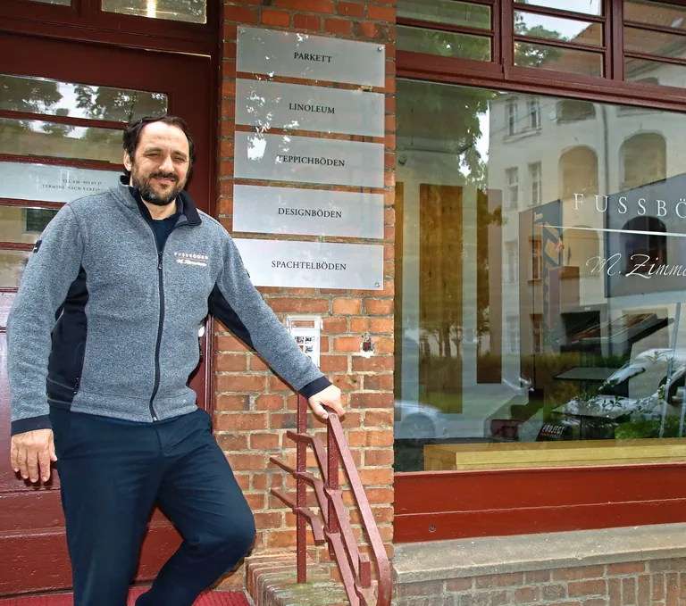 Mike Zimmermann auf der Treppe vor seinem Gesch&auml;ft in Berlin