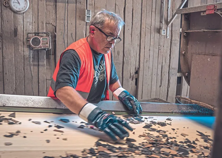 Mann sortiert Belagsreste am Band - Recover Recyclingprogramm Unilin