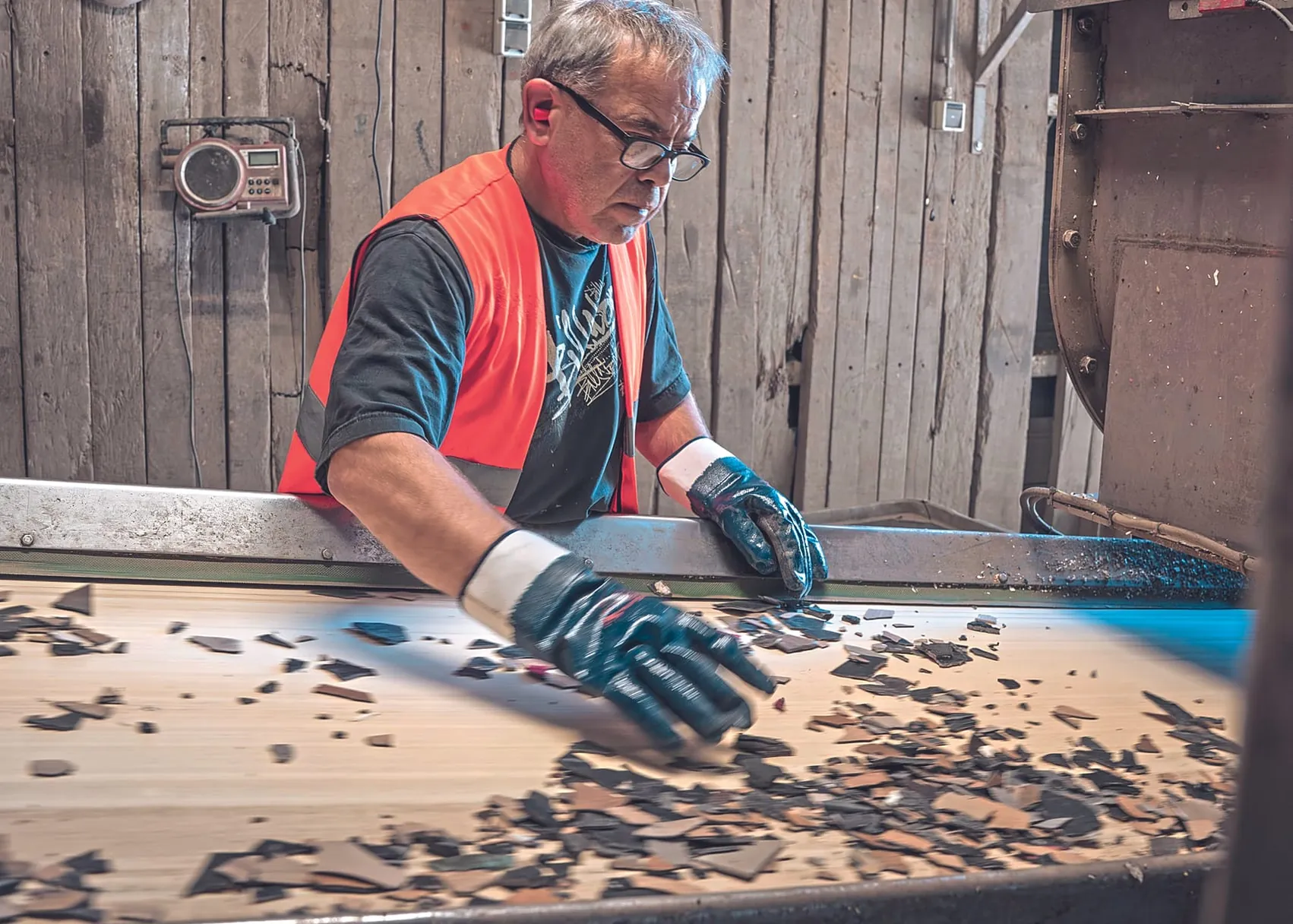 Mann sortiert Belagsreste am Band - Recover Recyclingprogramm Unilin